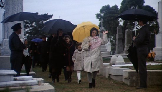 Dame Marjorie Chardin, alias Maude, with a yellow umbrella.